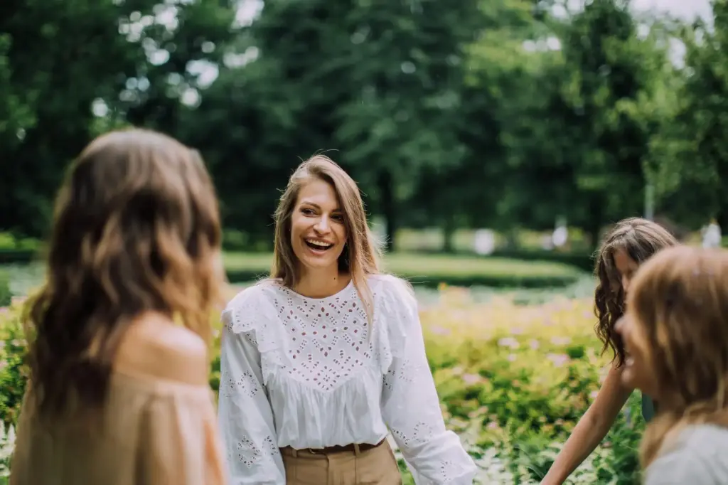 A group of friends laughing and enjoying an outdoor park setting on a sunny day.