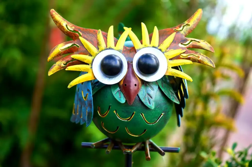 Vibrant metal owl sculpture with exaggerated features in a garden. Perfect decor inspiration.
