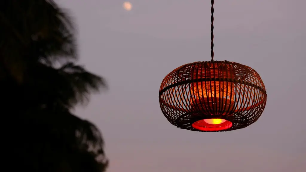A woven lantern glows warmly at twilight, set against a serene evening sky.