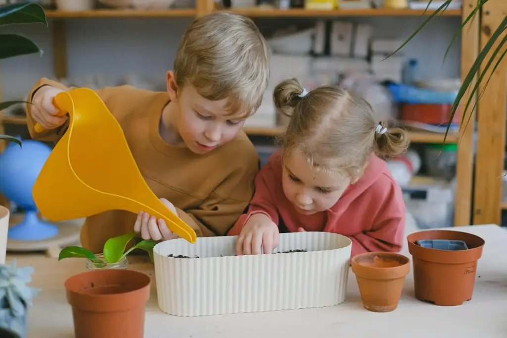 Two children planting seeds in pots indoors, learning about gardening and nature.