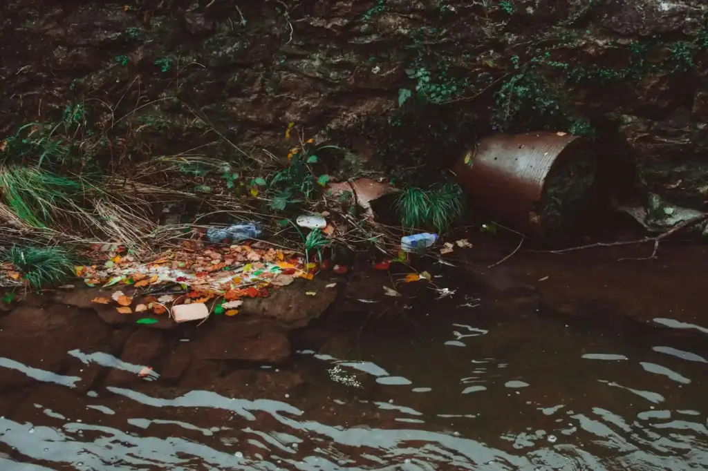 A riverbank littered with trash, highlighting environmental pollution and the need for recycling efforts.