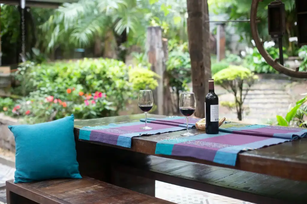 Charming garden patio setting with a wooden table, wine glasses, and a bottle set for relaxation.