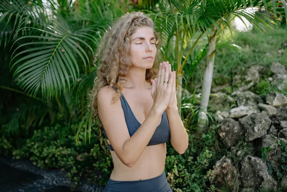 Woman in yoga pose with eyes closed, embracing tranquility amidst lush greenery.