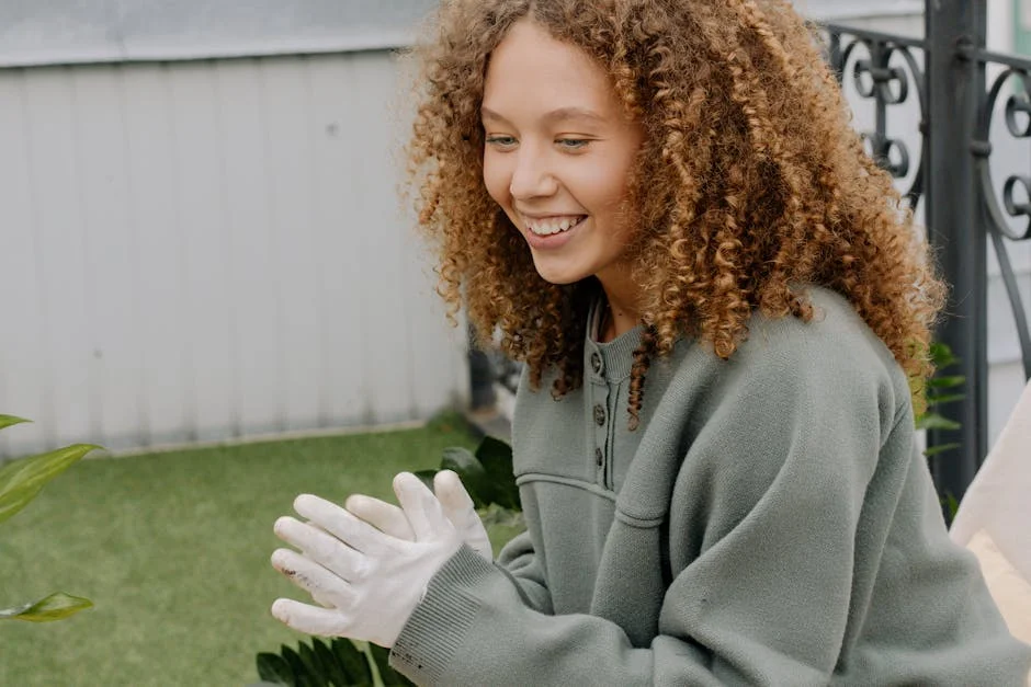 Cheerful young woman with curly hair wearing gloves, smiling outdoors.