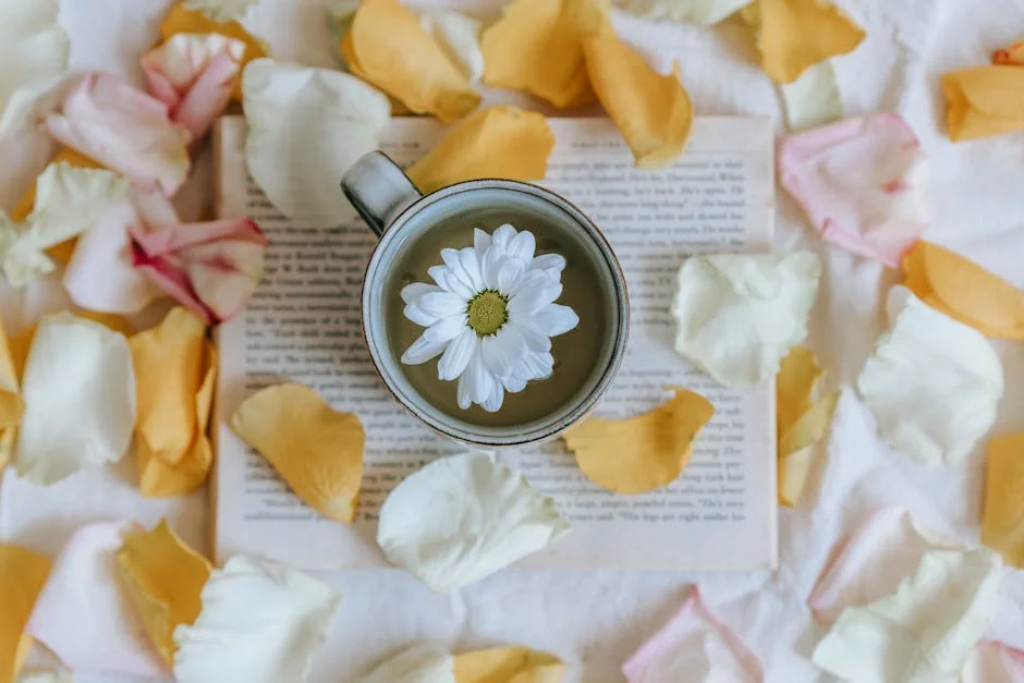 A charming scene of a white flower in a teacup surrounded by petals and an open book.