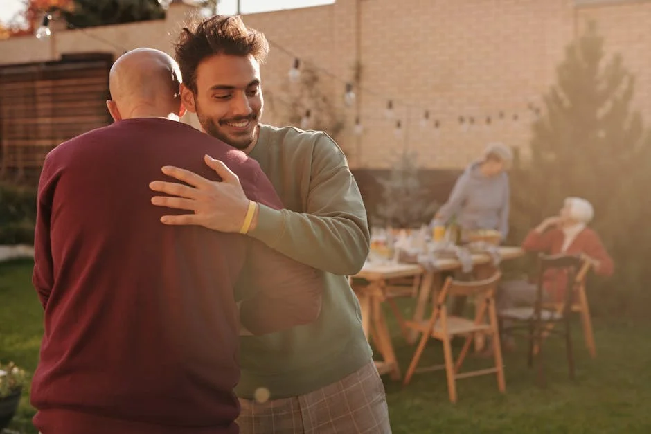 Two men hugging at a lively outdoor gathering with family and friends.