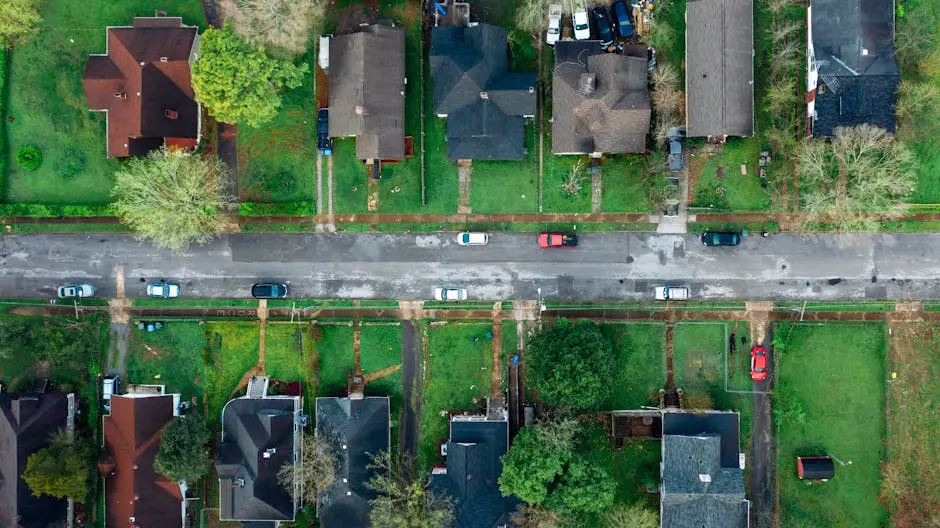 High-angle aerial shot of a suburban neighborhood street lined with houses and cars.
