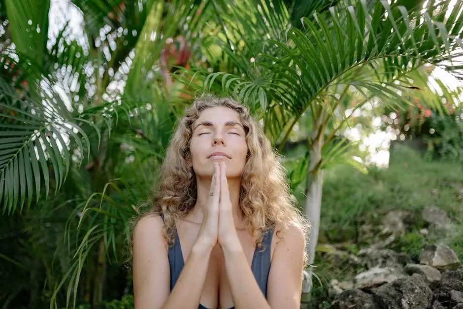 Woman practicing meditation with clasped hands in a lush, green tropical outdoor setting.