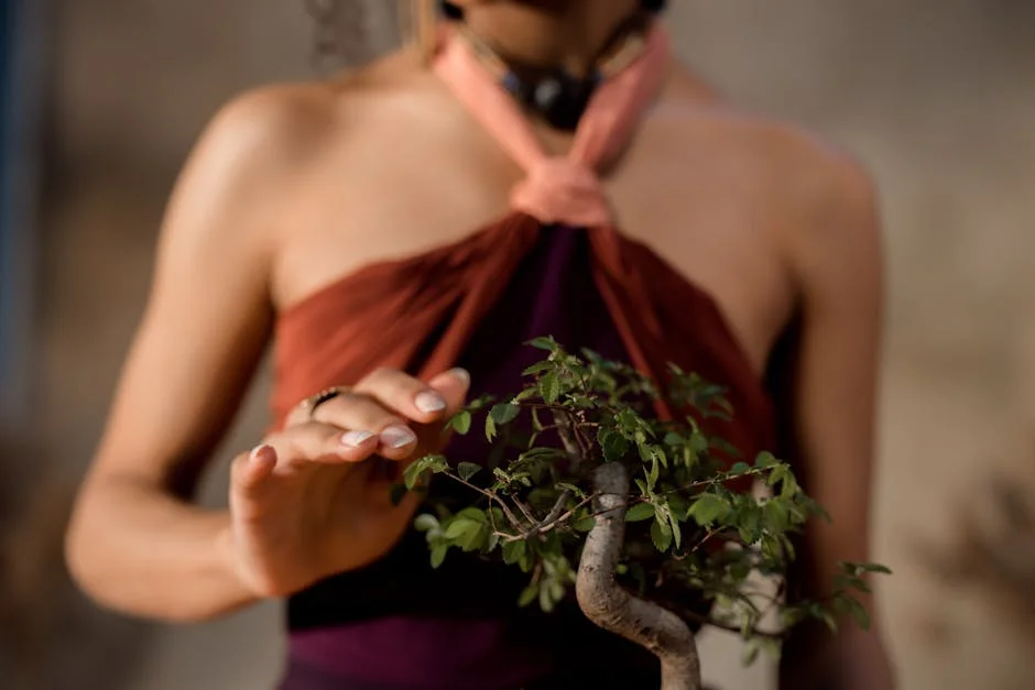 A woman gently interacting with a bonsai tree, showcasing intimacy and nature in a warm setting.