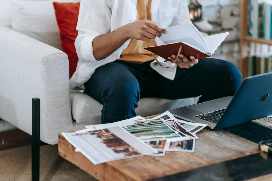 Man reviewing images and notes at a cozy workspace with laptop and notebook.