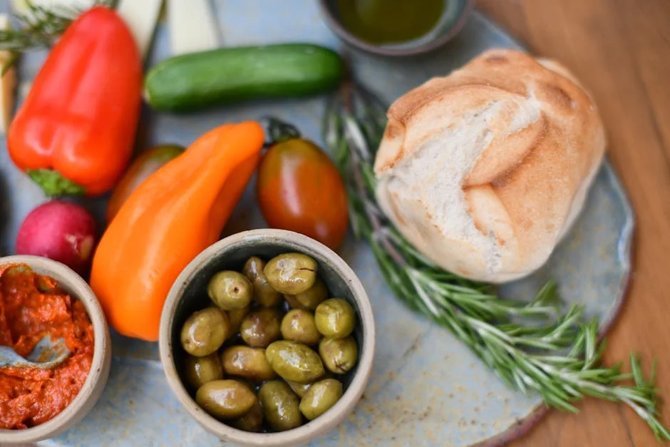 Top view of peppers, olives, and bread on a rustic plate.