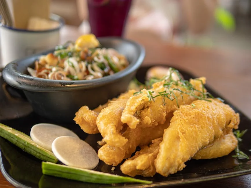 Delicious crispy fried fish paired with a vibrant Asian noodle salad, garnished attractively.