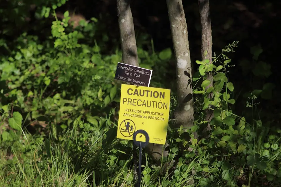 Close-up of a caution sign warning about pesticide application near green plants.