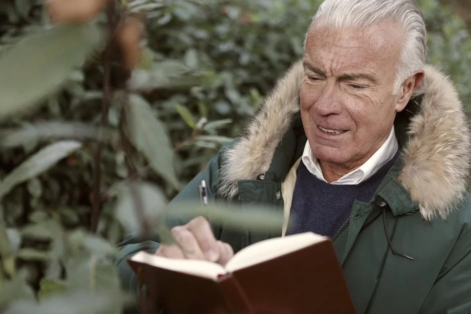 Senior man in a fur-lined coat writing in a notebook outdoors.