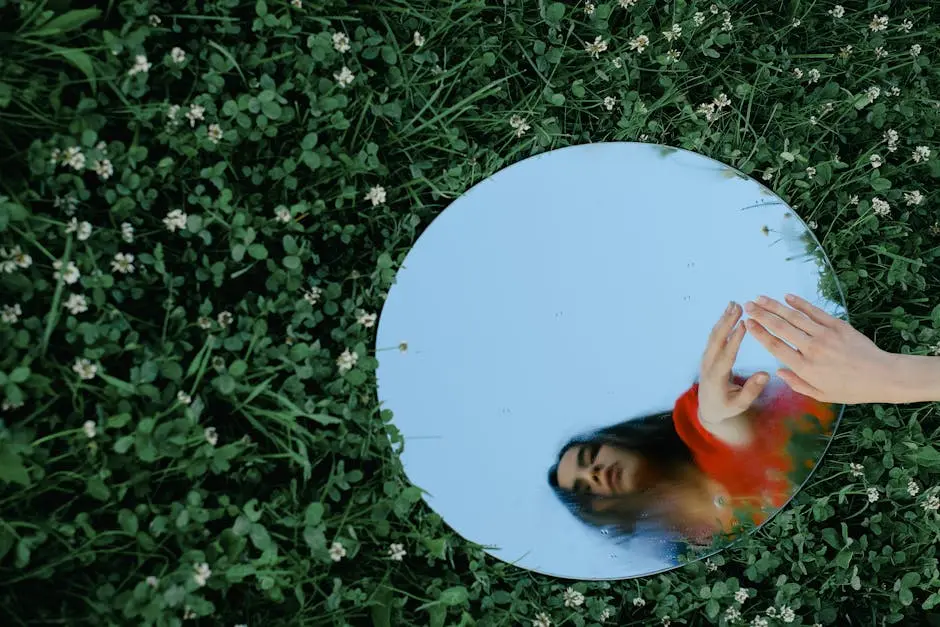 Artistic shot of a woman reflected in a mirror placed on grass, creating a surreal outdoor scene.