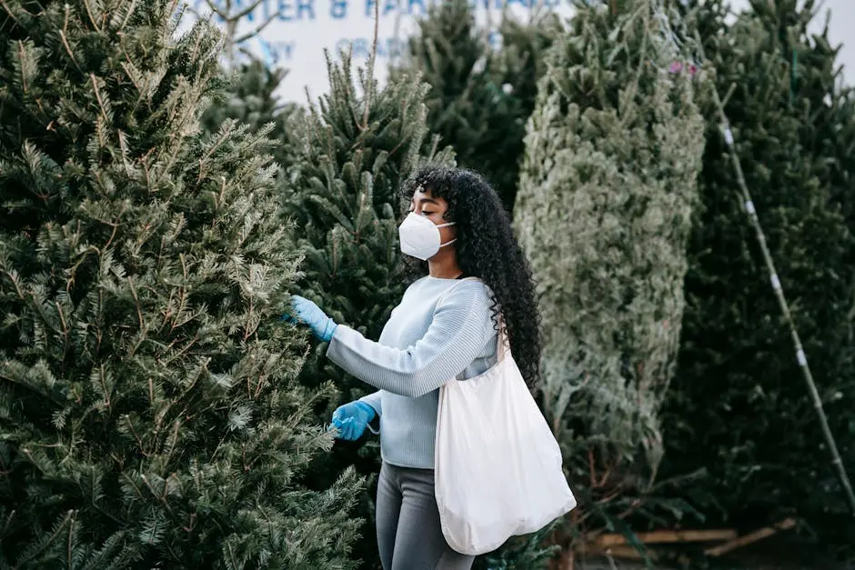 Side view of African American female in protective mask and gloves choosing tall green coniferous tree while standing in market