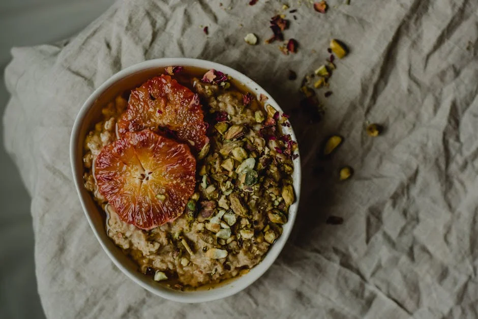 Delicious porridge bowl topped with blood orange and pistachios in a still life setting.