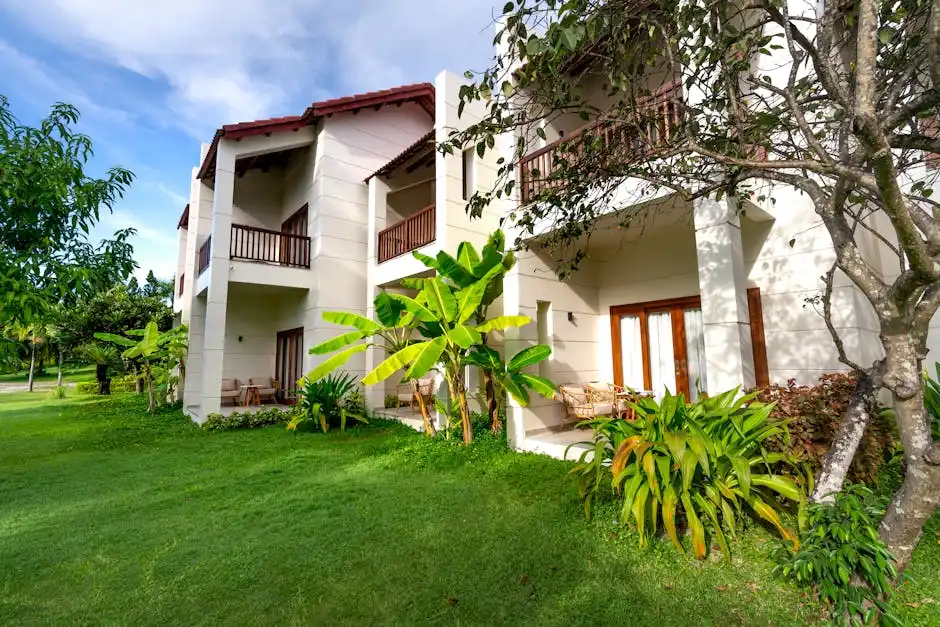 A contemporary residential building with a lush green lawn and tropical plants.