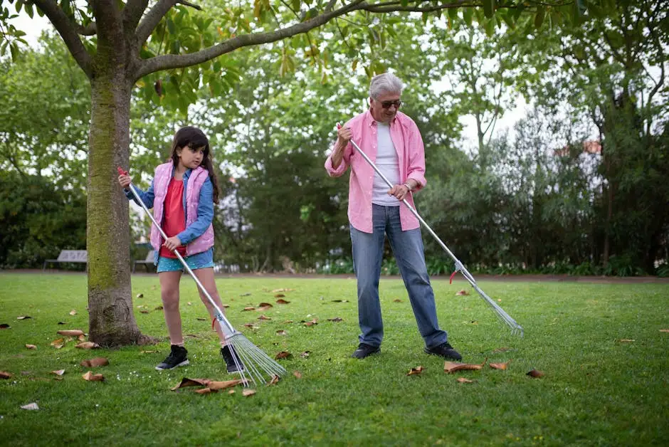 Warm family moment outdoors with grandfather and granddaughter raking leaves in a park.