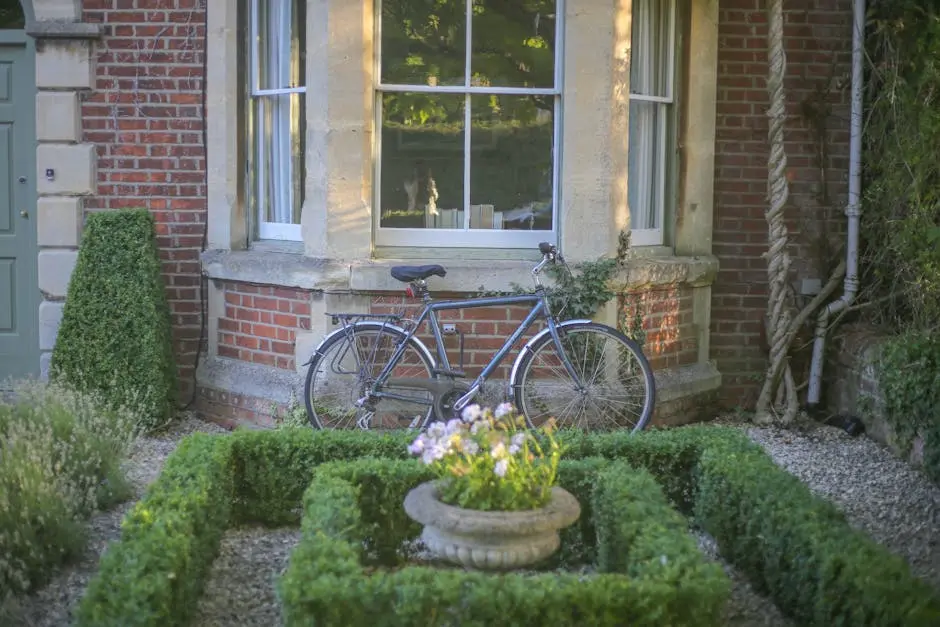A bicycle leans against a brick house with a lush garden, ideal for serene outdoor living.