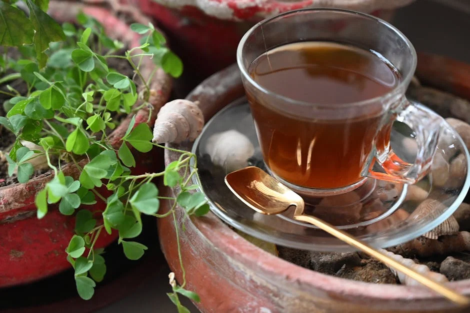 A glass tea cup and spoon on a saucer amidst garden pots, evoking a serene vibe.