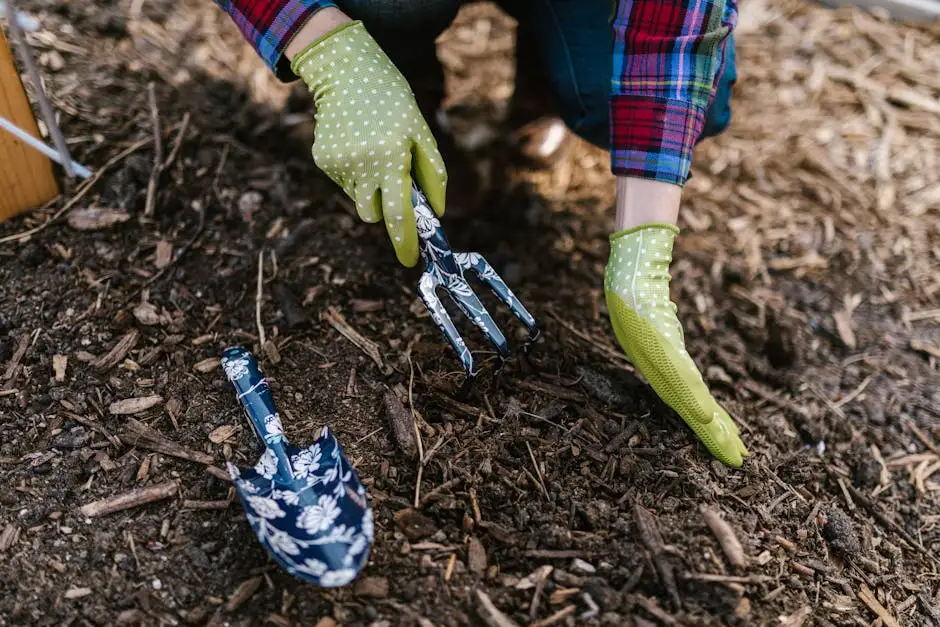 A person wearing gloves using garden tools in soil for planting.