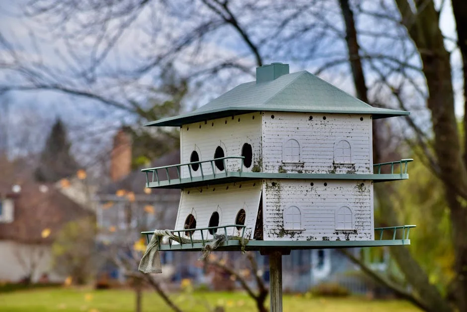 A detailed view of a two-story birdhouse in a serene backyard garden.