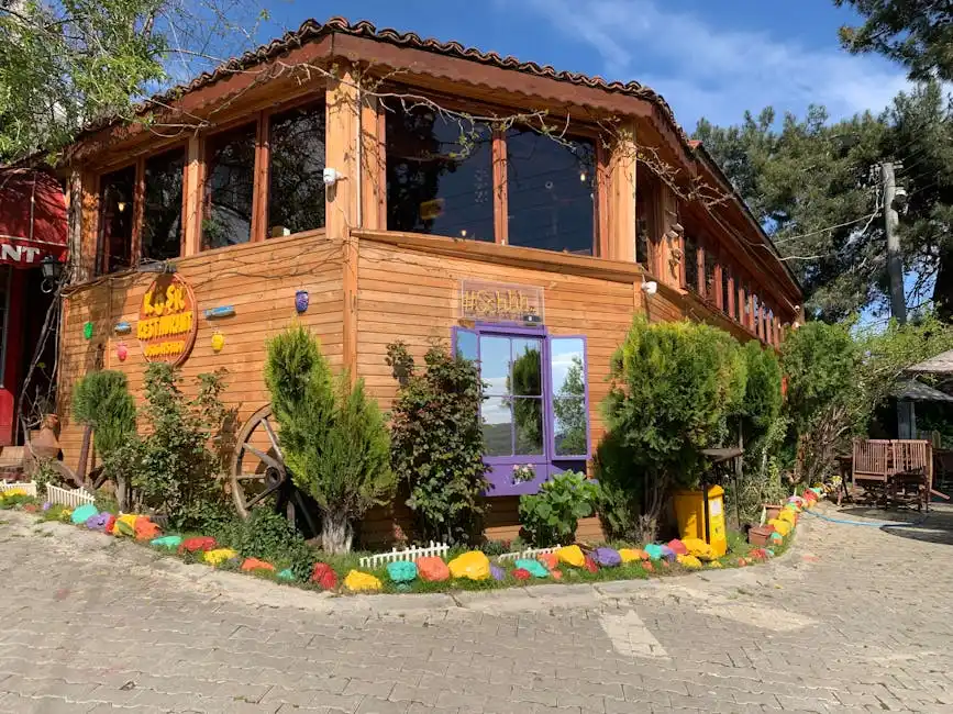 Rustic wooden restaurant facade with vibrant garden accents and clear sunny sky.
