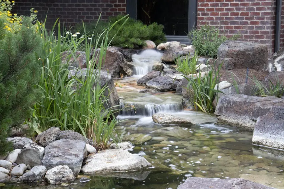 Serene garden pond featuring cascading waterfalls surrounded by lush plants and rocks.
