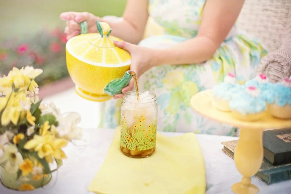 Enjoy a delightful outdoor tea party with iced tea, cupcakes, and floral decor in a serene setting.