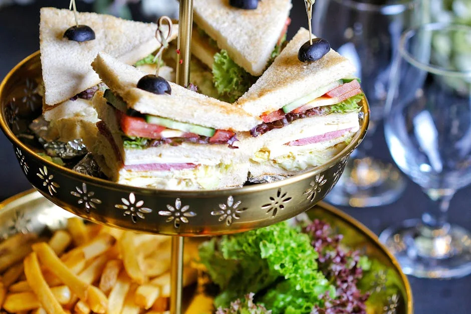 Delicious club sandwiches elegantly presented with fries and salad garnish on a golden platter.