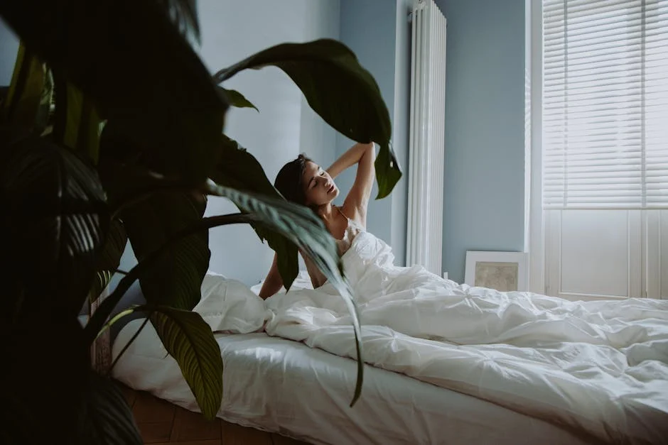 A woman waking up in a cozy bedroom with natural light and lush greenery.