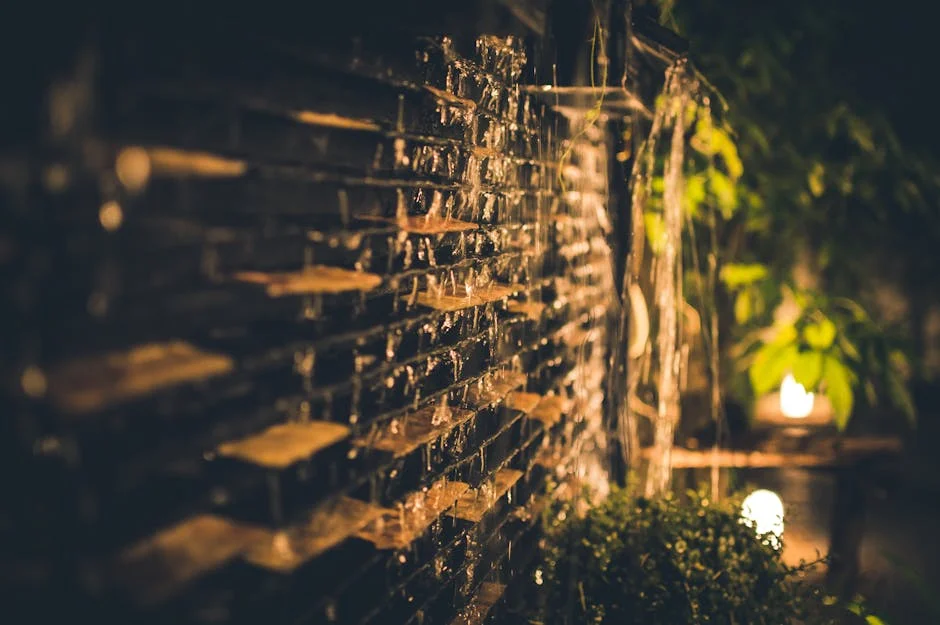 A serene and illuminated garden waterfall captured at night, featuring cascading water over bricks and soft ambient lighting.