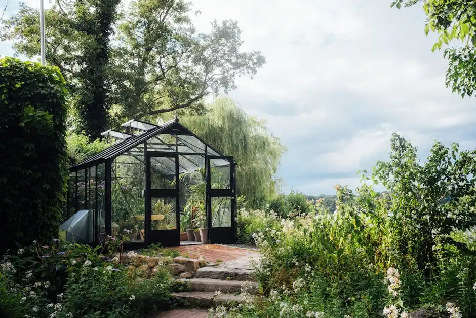 A picturesque greenhouse nestled in a vibrant garden surrounded by greenery and trees under a bright sky.