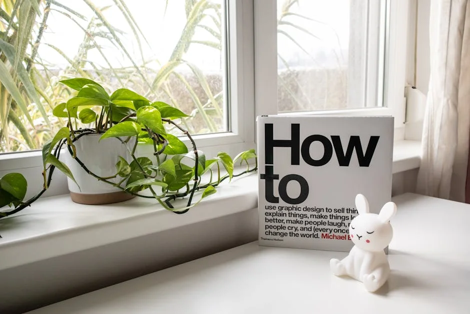 A contemporary interior setup with a book, a potted pothos plant, and a bunny figurine on a windowsill.