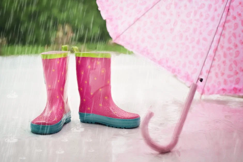 Pink rain boots and umbrella on a rainy day, creating a playful and colorful scene.