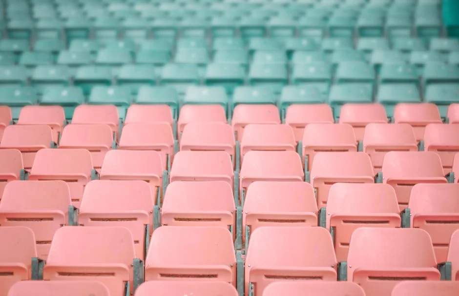 Empty pastel pink and mint green stadium seats, artistically arranged in rows.