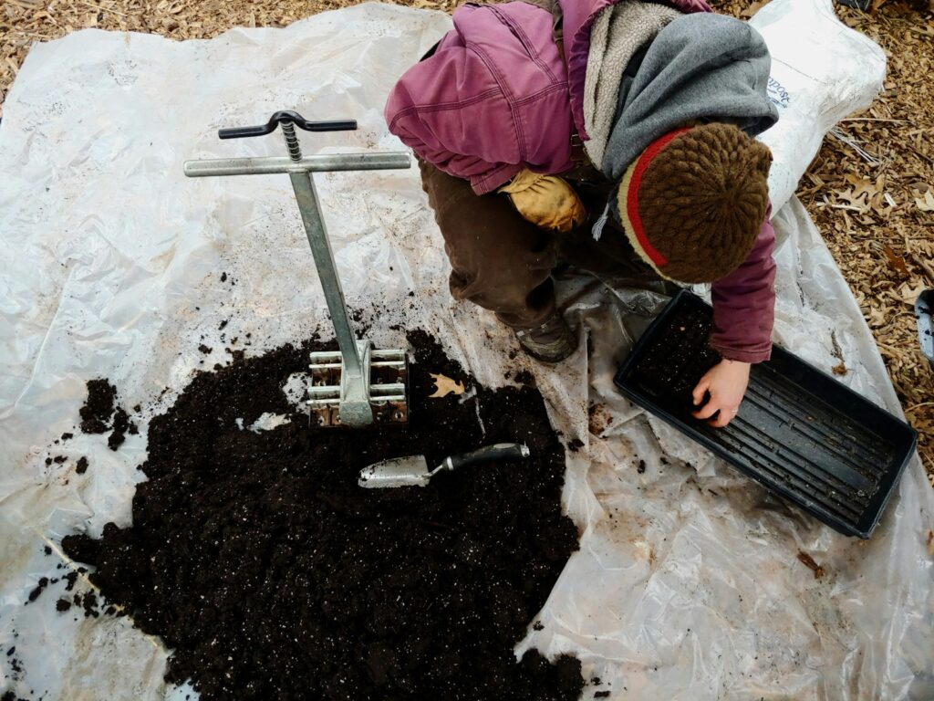man kneeling beside black soil