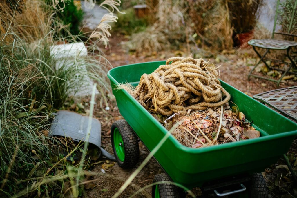 a green wheelbarrow filled with a pile of rope