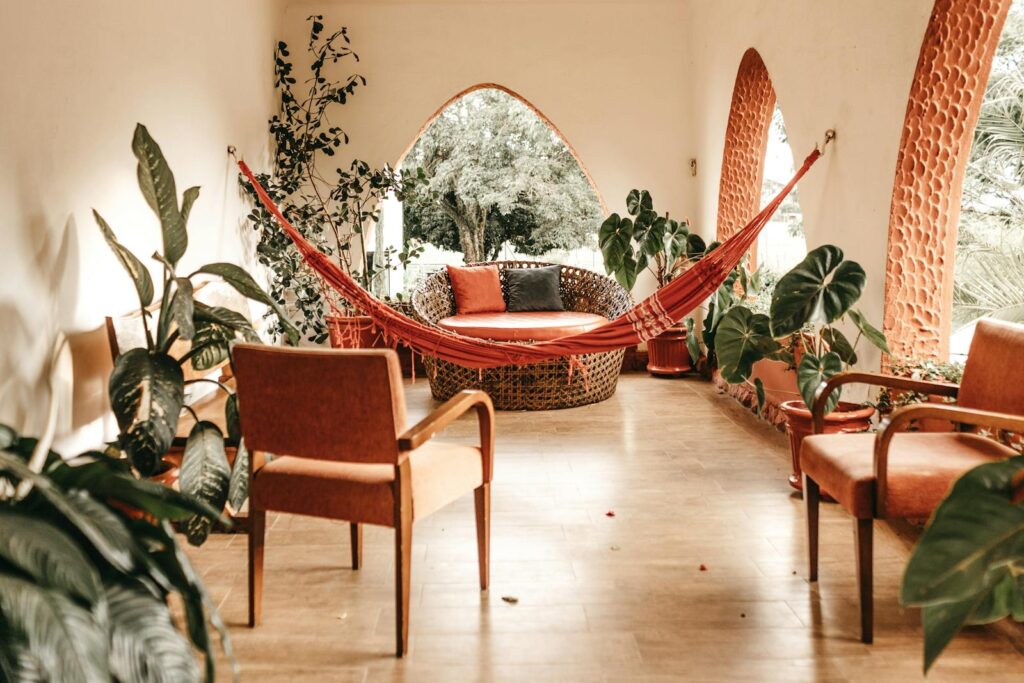 Inviting indoor patio with hammock, rustic chairs, and lush plants showcasing modern design.