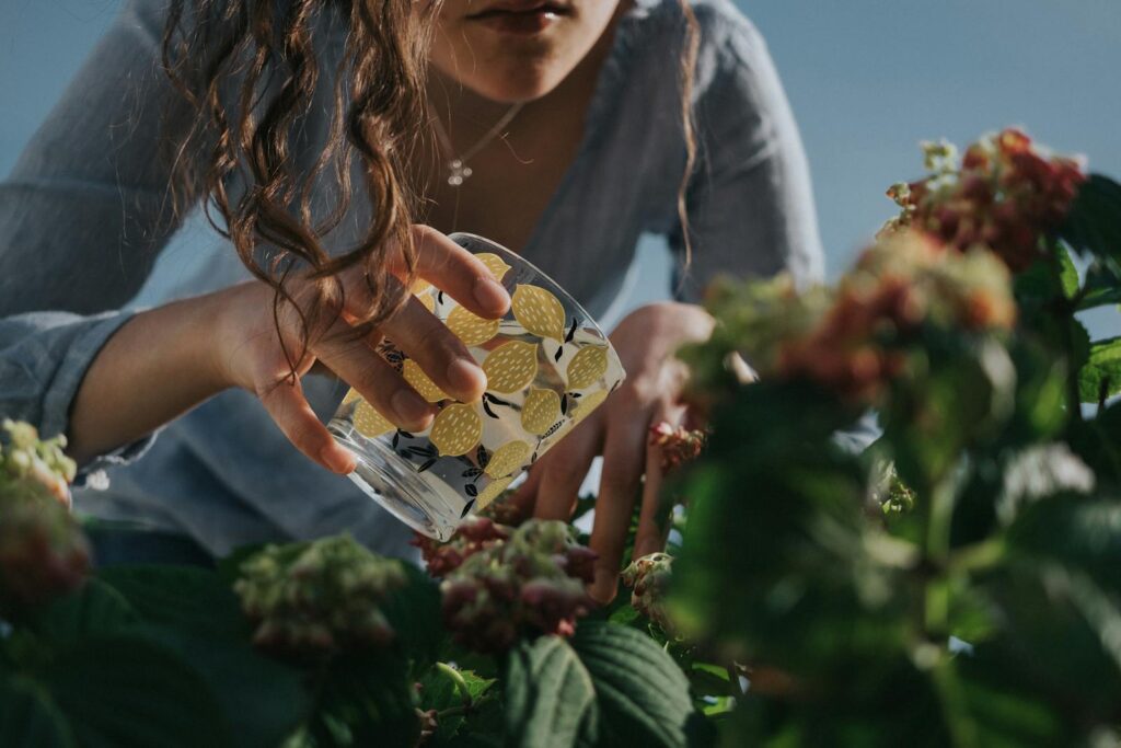 Close-up of a woman watering plants in a garden during the summer season.