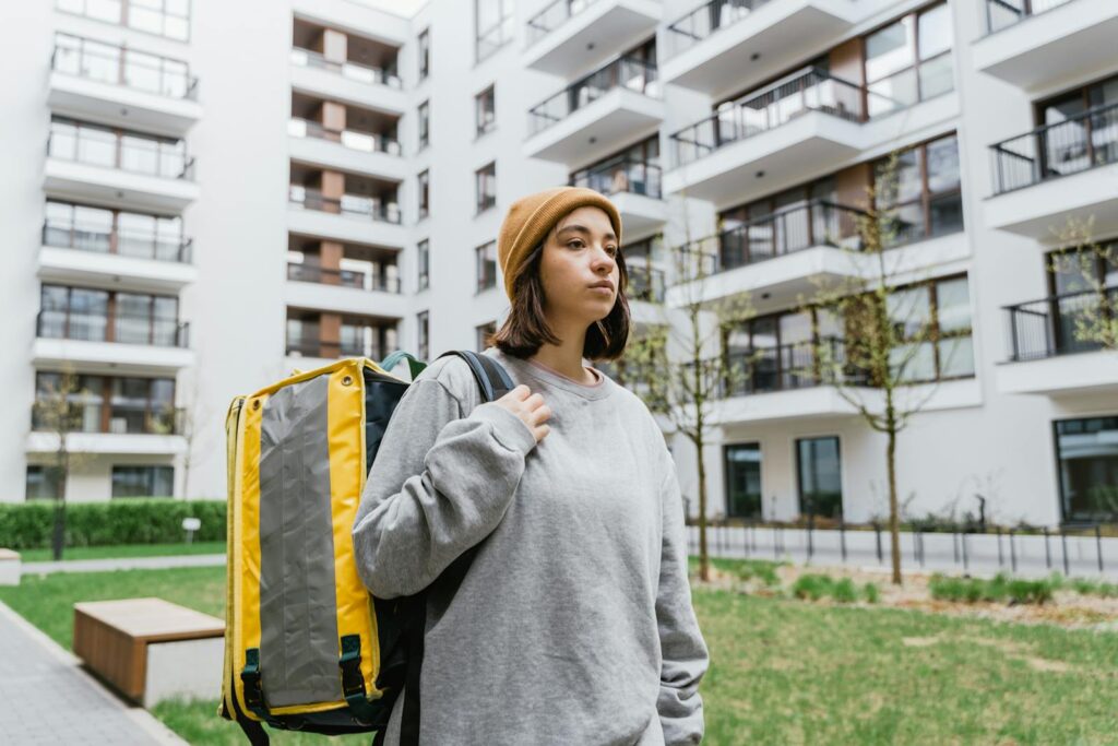 Young delivery person with thermal bag in urban setting, ready to deliver.
