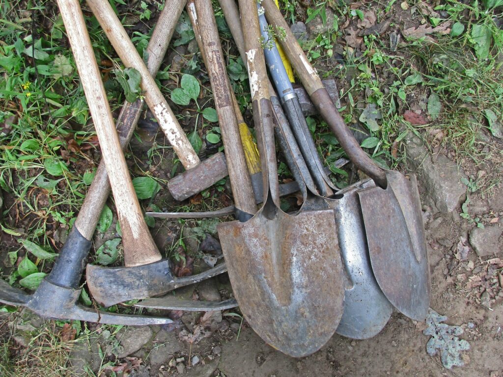 a pile of shovels and forks laying on the ground