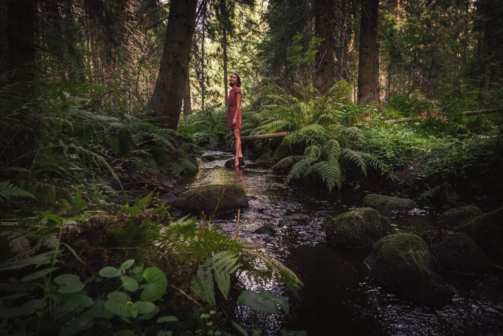 woman in red dress standing on river during daytime