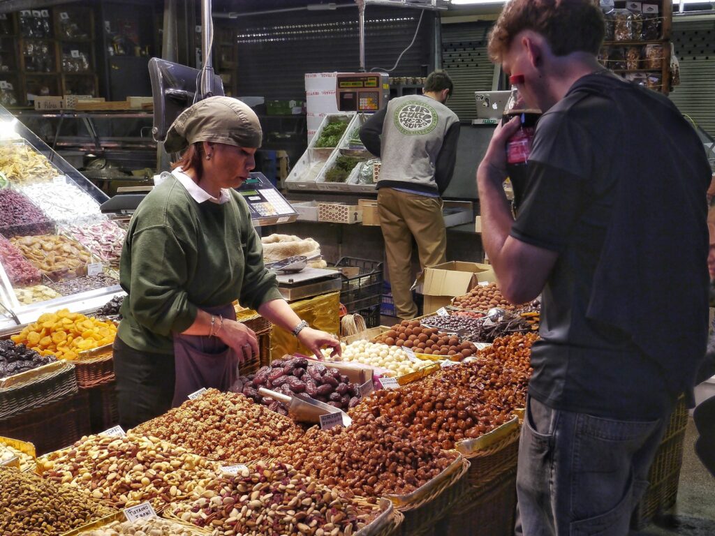 Vendor selling nuts and dried fruits at market stall.