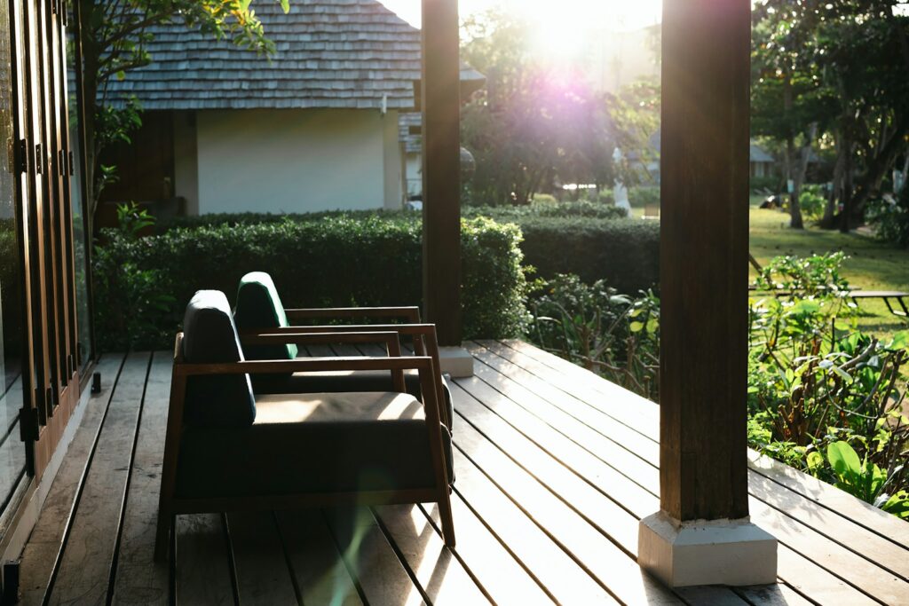 A wooden deck with chairs and a house in the background