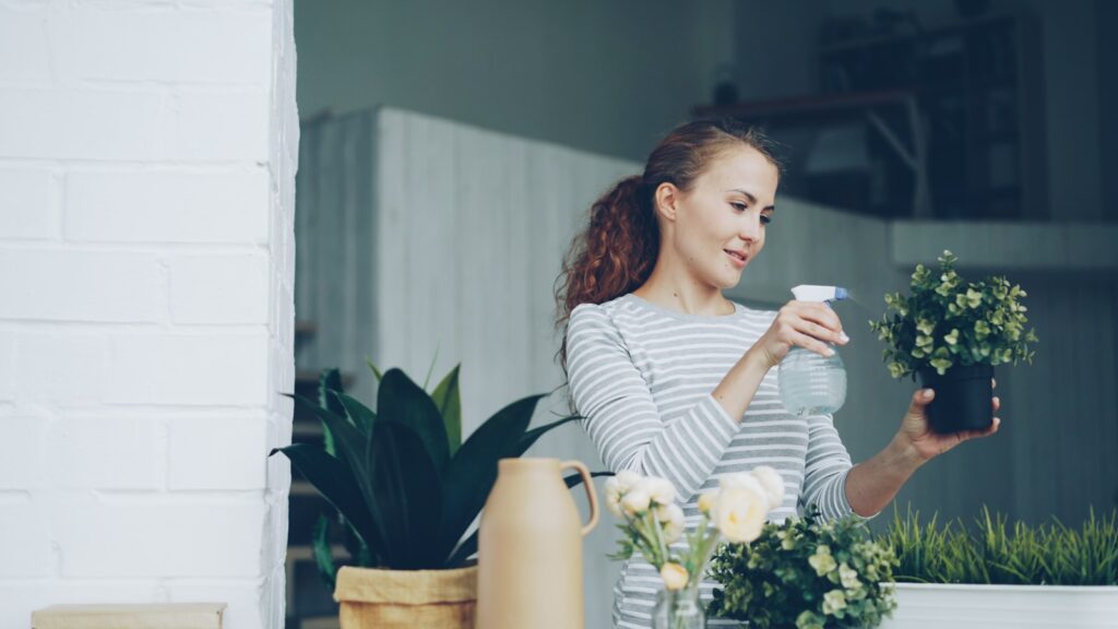 Woman watering plants on a balcony.