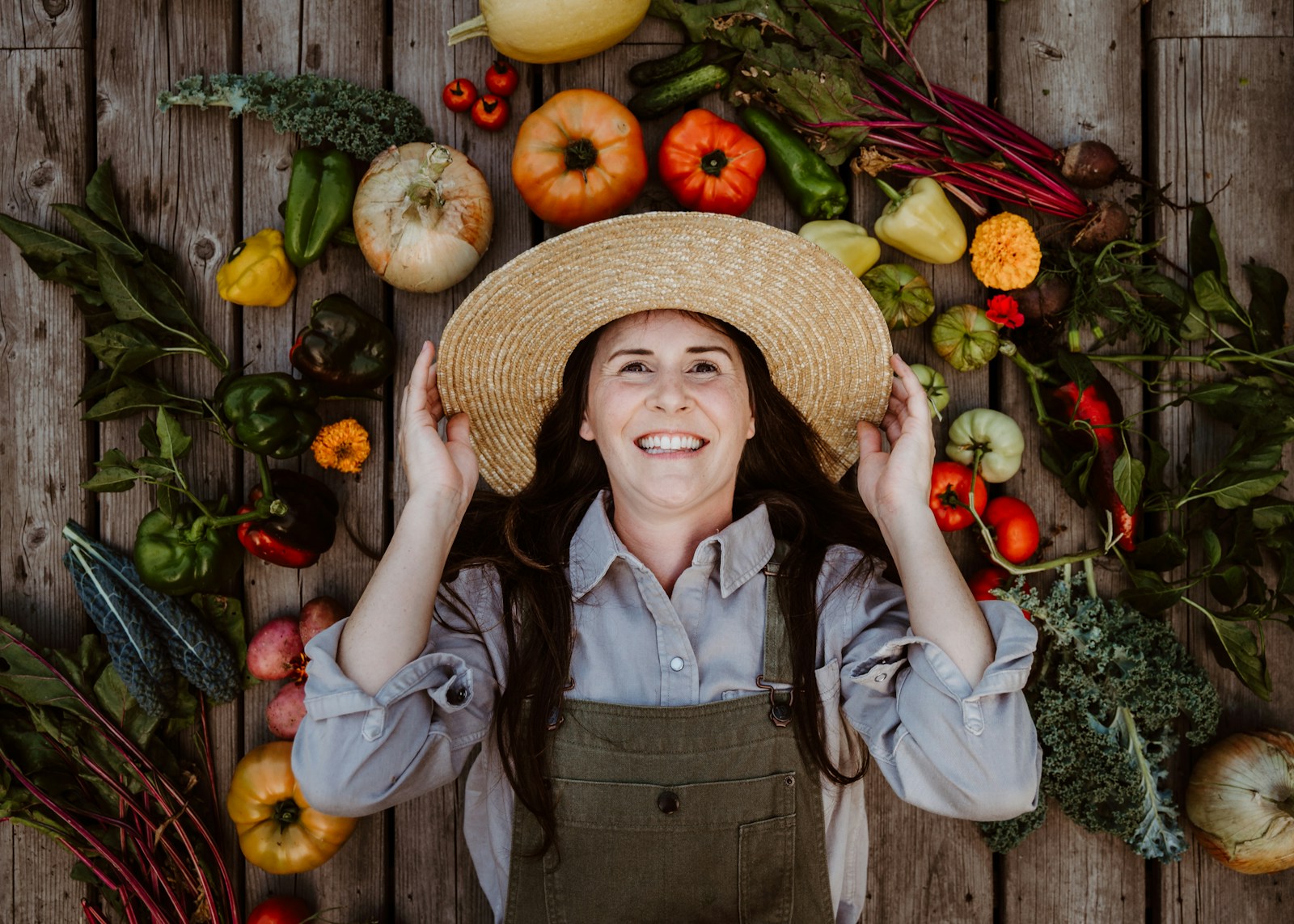 A woman wearing a straw hat surrounded by fruits and vegetables