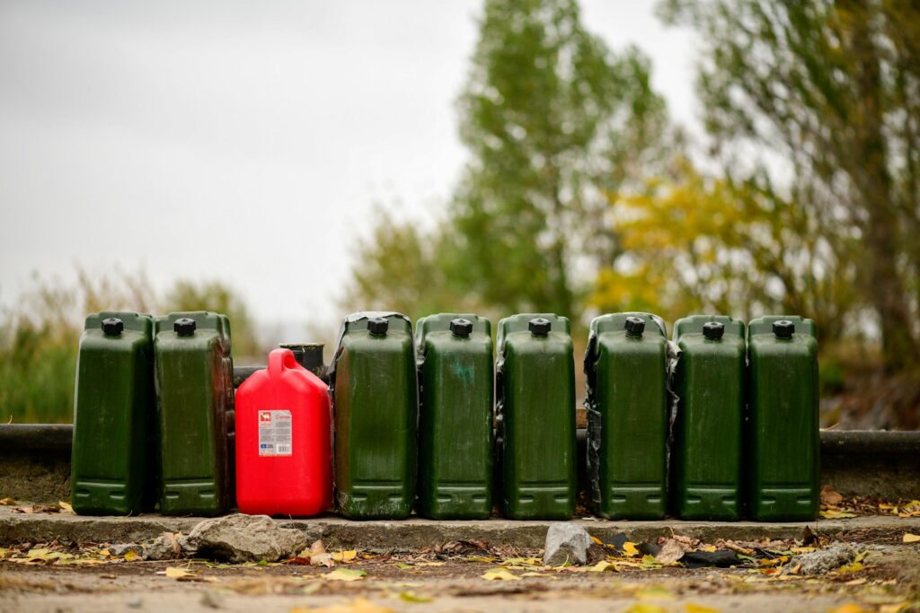 A row of green and red gas cans sitting on the ground