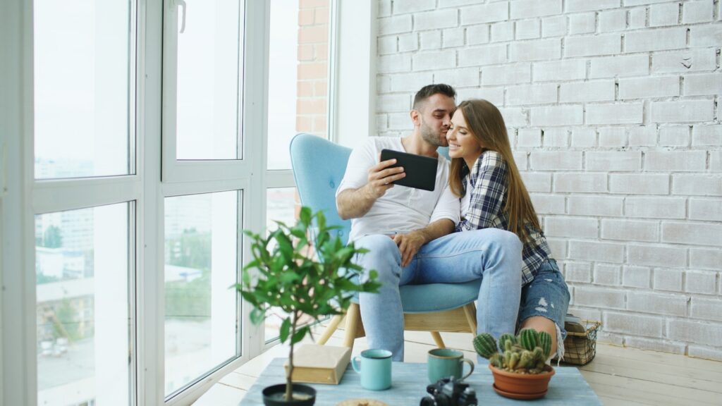 Couple looking at tablet in a bright room.